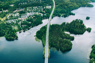 Wall Mural - Aerial view of road bridge with cars between green forests and blue lakes in rural Finland