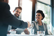 © N Hiraman/peopleimages.com - Business people, handshake and meeting for partnership, teamwork or collaboration in boardroom at office. Happy woman shaking hands in team recruiting, introduction or b2b agreement at the workplace