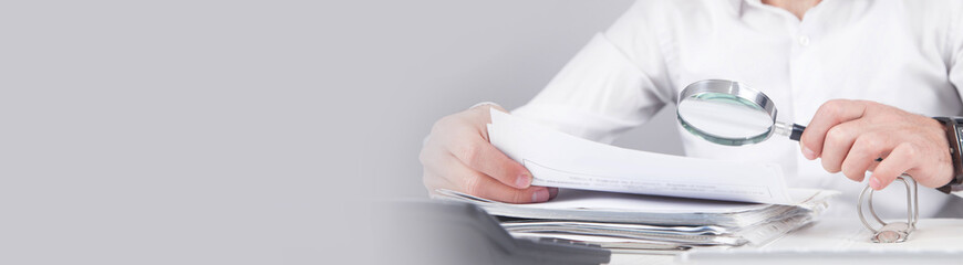 Poster - Man holding magnifying glass with documents.