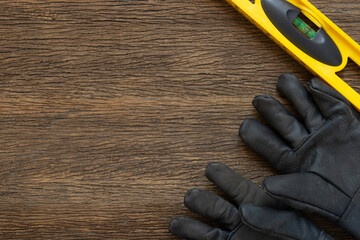 Wall Mural - Yellow building water level gauge and gloves on the old wood table, engineering work tool concept