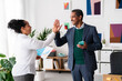 © Studio Marmellata - Positive adult Ethiopian couple in elegant clothes smiling and looking at each other while giving high five in modern office