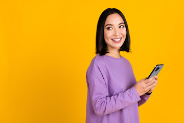 Wall Mural - Photo of young influencer japanese woman black hair hold phone look empty space online facebook page isolated on yellow color background