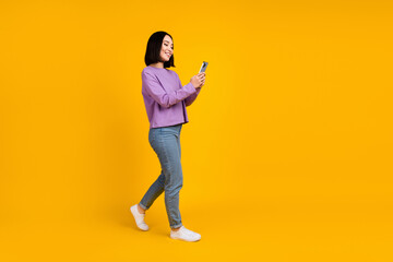 Sticker - Full body size photo of young chinese blogger girl hold phone walking recording video online popularity isolated on yellow color background