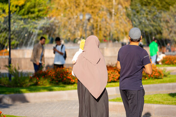 Wall Mural - Muslim family spend time together in the park. Girl in a hijab. Romantic Muslim couple in love with a baby in their arms.