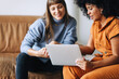 © (JLco) Julia Amaral - Happy young businesswomen using a laptop together in an office lobby