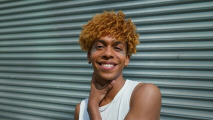 Wall Mural - Happy handsome young man with makeup and in casual clothes posing on the street