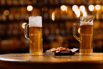 two glasses of beer in the hands of men, friends in a bar, an evening in a pub, close-up