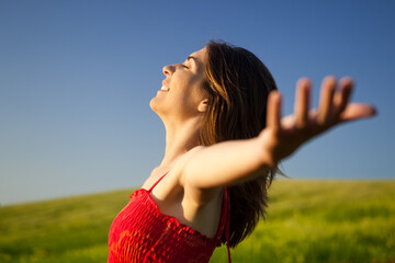 Wall Mural - Portrait of beautiful young woman relaxing on the field with both arms open