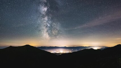 Wall Mural - starry night sky in mountains time lapse with milky way galaxy stars motion fast over countryside tr