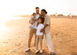 © Prostock-studio - Family moments on the beach. Happy diverse parents with little kids enjoying time at sea, full length shot, free space