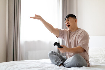 Wall Mural - Angry asian man playing video games at home