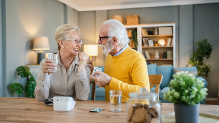 senior couple at home woman take medicine while her husband sit beside