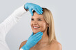 © Prostock-studio - Plastic surgeon doctor touching middle aged woman face