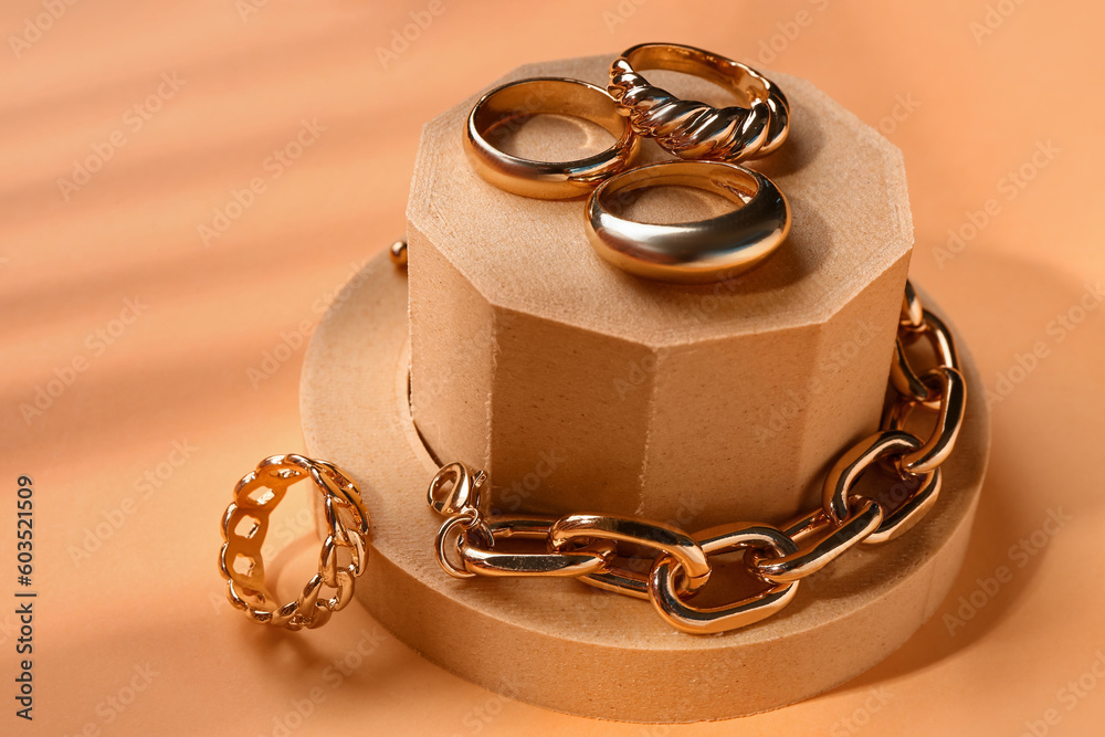 Decorative podiums with golden ring and bracelet on orange background