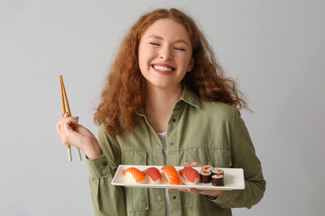 Young woman with sushi on light background