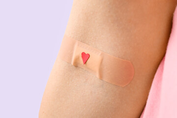 woman with applied medical patch on lilac background, closeup. world blood donor day
