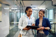 © Drazen - Smiling businesswomen cooperating while using touchpad in office.