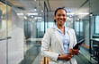 © Drazen - Happy black female CEO with touchpad in office looking at camera.
