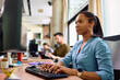 © Drazen - Black female entrepreneur working on desktop PC in office.