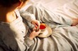 © Joaquin Corbalan - A young woman drinks tea in her bed in her pajamas, to recover from an illness. Ai generated.