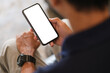 © wattana - Over shoulder view of man using smartphone with blank screen for your advertise or text message.