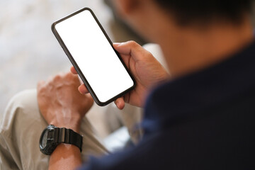 Over shoulder view of man using smartphone with blank screen for your advertise or text message.