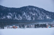 Houses on the bank of frozen Teletskoe lake under the chimney smoke. Iogach, Altai.
