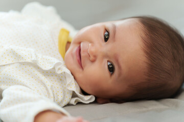 happy infant baby smilling while lying on bed