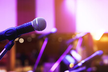 Close Up Of Microphone On Stage Lighting At Concert Hall Or Conference Room. Copy Space Banner. Soft Focus.