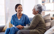 © Tinashe Njaku/peopleimages.com - Retirement, sofa and caregiver with senior woman for conversation, chatting and support in living room. Healthcare, nursing home and female nurse with elderly patient for wellness, comfort and help
