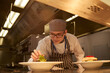 © Connect Images - Young cook garnishing plate in kitchen