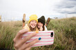 © Connect Images - Smiling girl friends lying in grass and taking selfie