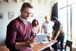 © Koegelenberg/peopleimages.com - Man, tablet and working in office meeting with team in creative workspace and planning, research and management. Businessman, happy teamwork and web design leader with technology for project