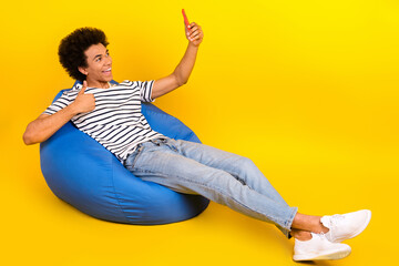 Full length photo of lying pouf young blogger man thumb up paid advert recording face portrait isolated on yellow color background