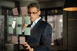 © JustLife - Portrait of successful businessman in office. Man writing ideas on colorful stickers on glass wall.