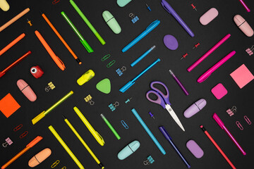 Creative pattern made of neon colorful stationery set on black background.