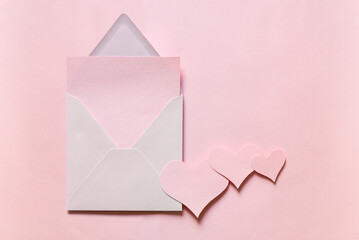 Canvas Print - Blank greeting card mockup. Light empty sheet of paper mockup in an envelope. Three hearts from pink paper. flat lay. Wedding, birthday still life scene.