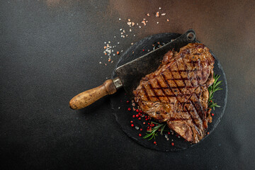 T-bone grilled beef steak with spices on a dark background. Restaurant menu, dieting, cookbook recipe