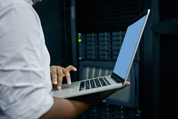 Server room, man or hands of technician with laptop for online cybersecurity glitch or software. IT support, closeup or electrical engineer coding data or fixing network for information technology