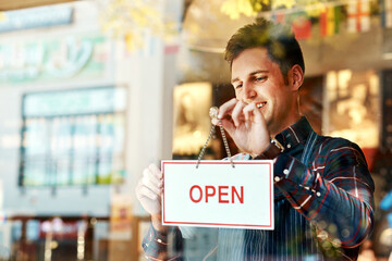 Coffee shop, open sign and a man small business owner standing a glass door for service or hospitality. Cafe, manager or employee with a happy male waiter proud to be opening a new restaurant