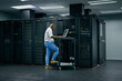 Server room, database and information technology with an engineer man at work on a network mainframe. Computer, programming and cybersecurity with a male technician working in IT support or safety