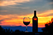 Silhouette of a glass of red wine and wine bottle at sunset with Virginia mountains in the background.