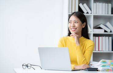 Poster - Young Asian female office worker working with laptop computer in the office room.