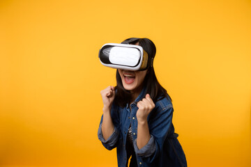 Poster - Young asian woman get experienced wearing virtual reality headset game entertainment isolated on yellow background. Winner of cyber future video game concept.