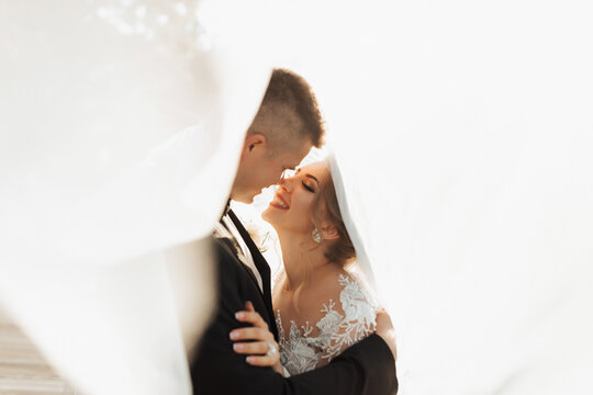 wedding portrait. the groom in a black suit and the blonde bride are hugging, wrapped in the bride's