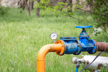 Close up of manometer measuring water pressure. Pipes and valves at industrial plant.