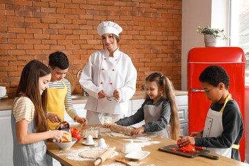 Canvas Print - Female chef with group of little children preparing pizza during cooking class in kitchen