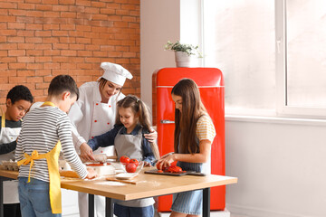 Canvas Print - Female chef with group of little children preparing pizza during cooking class in kitchen