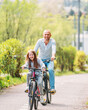 © Soloviova Liudmyla - Portraits Smiling father with daughter during summer outdoor bicycle riding. They enjoy togetherness in the summer city park. Happy parenthood and childhood or active sport life concept image.