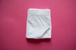 Folded white panties on a pink background. Step 4. Storage by method, organization, closet, underwear, minimalist briefs. Step-by-step folding of panties. Mockup. Briefs. Stacked cotton underwear
